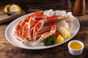 Pre-Cooked Crab Legs With Melted Butter on a Platter on a Wooden Table