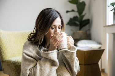 一个女人在家里喝茶作为一个自然治疗喉咙痛