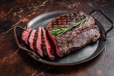 Grilled Medium Rare top sirloin beef steak or rump steak on a steel tray. Dark background. Top view