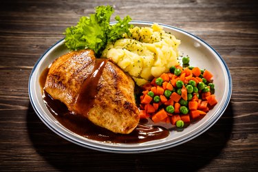 Fried chicken breast, mashed potatoes and vegetables on wooden background