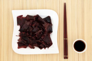 Dulse Seaweed rehydrated on a white plate next to chopsticks and soy sauce.