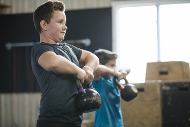 两个孩子举起kettlebells在健身房