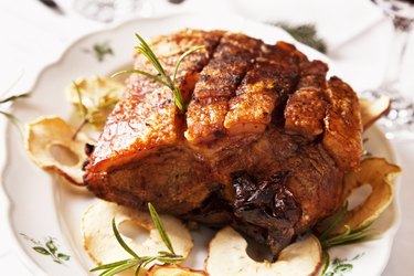 Four-pound Bone-in pork roast on a plate with herbs on a white plate