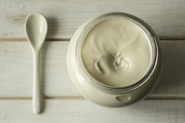 Jar with mayonnaise and a spoon on a wooden board. top view.