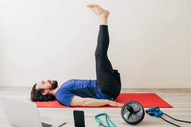 Person performing a Pilates exercise on yoga mat in living room to ease neck pain