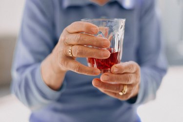 Senior person's hands holding a glass of tart cherry juice