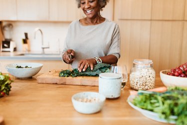 Senior female chopping vegetable at kitchen island