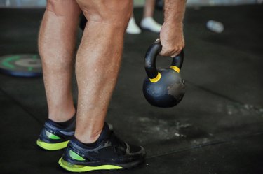 Older man taking hold of kettlebell to perform total-body workout over 50