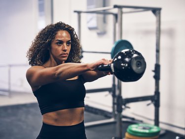 fit woman doing a kettlebell swing at the gym