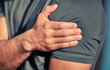 closeup shot of a person holding their shoulder, considering whether or not to do a strength workout after a flu shot