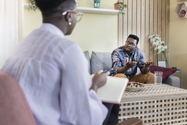 Person assigned male at birth sitting on couch talking to therapist