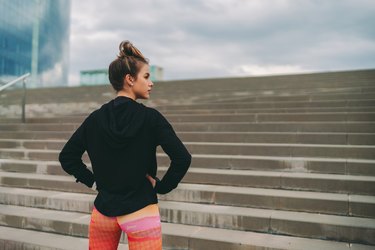 young woman standing in front of outdoor staircase before workout