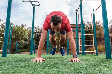 Athletic fitness man doing burpee exercise. Fit male in gym exercise outdoors. Healthy lifestyle. Strength cardio on the sport ground