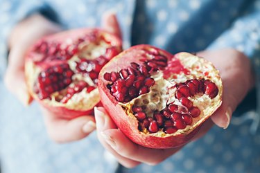 a person holding a pomegranate cut in half