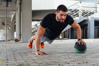 man performing push ups with medicine ball outside