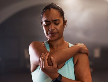 Shot of a young woman experiencing pain while working out in a gym