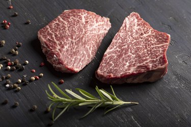 Wagyu beef filet with pepper and rosemary on black background