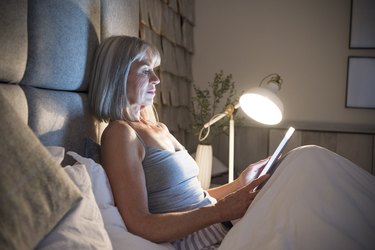 Senior woman propped up by pillows in bed, as a natural remedy for upset stomach