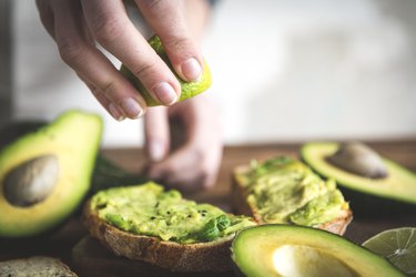 Hand squeezing lime onto magnesium- and potassium-rich avocado on toastwich