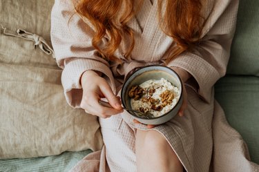 A woman hand holding a bowl of cereal, knowing what to eat for breakfast when sick