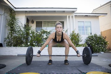 Woman doing dead lifts with weights at home