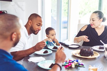 A family eats chocolate birthday cake at home together