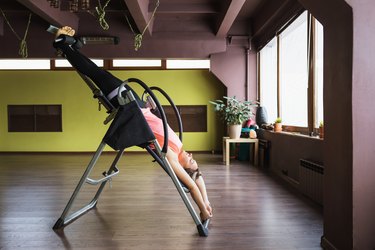A person doing inversion therapy hanging upside down on an inversion table in a studio