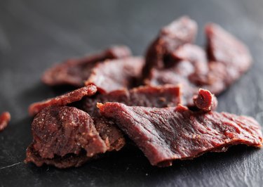 Strips of beef jerky shot with selective focus on wooden table