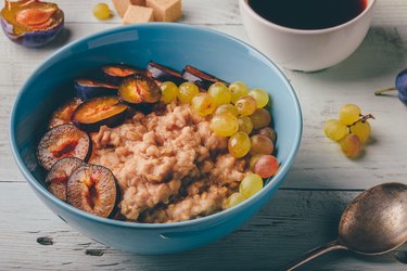 Porridge with fresh plum, green grapes and cup of coffee.