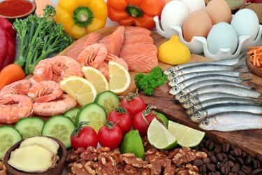 Fat-shrinking fruits, vegetables, nuts, fish, meat and eggs on a wooden background