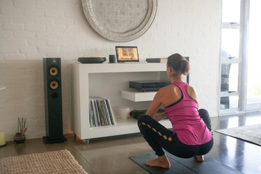 woman doing frogger squats at home in front of a tablet