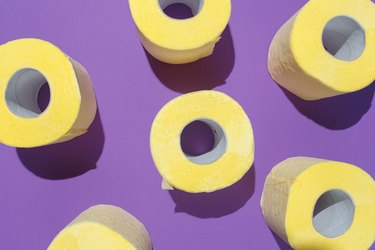 Pattern of bright yellow toilet paper rolls on purple background to represent different urine colors