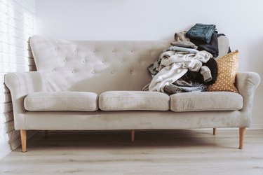 Pile of unfolded clothes for laundry on the sofa. Heap of used clothes for donation or recycling