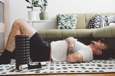 fit man lying down and feeling tired and sore after an at-home workout
