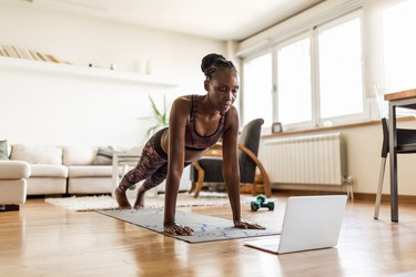 black woman doing push-ups in her living room at home