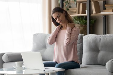 Tired woman feeling neck pain after computer work at home