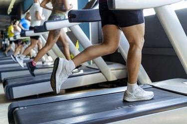 Male and female athletes running on treadmill in gym