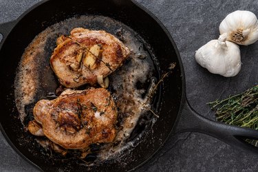 Biotin-rich pork chops in a cast iron skillet with fresh garlic and rosemary.