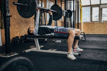 Person in gym performing the bench press exercise to build upper-body strength