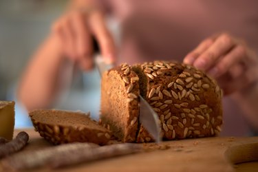 hand cutting slice of whole grain seeded bread