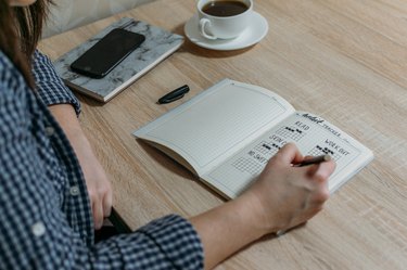 Person writing in a bullet journal at their desk