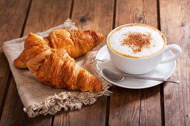 Cup of cappuccino coffee with croissants