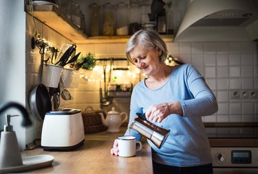 Senior woman making coffee in the kitchen at home