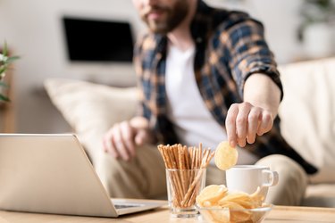 man eating chips because he has a food craving from dieting