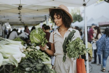 woman buying kale at a farmers market, as an example of food to keep your thymus healthy