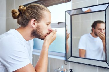 man in his bathroom at home checking his bad morning breath