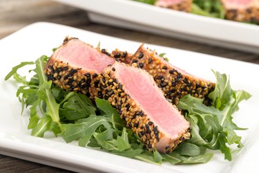 A bariatric patient should eat the calories in tuna tataki over arugula salad on a white plate
