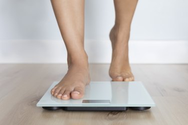 person's feet stepping onto a body fat scale