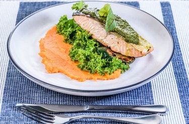 A seafood dinner serving of a piece of Kahawai with greens, pesto and mashed sweet potatoes