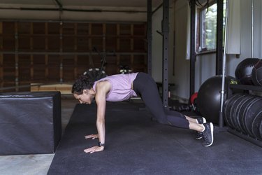 side view of a woman doing a burpee exercise in a gym